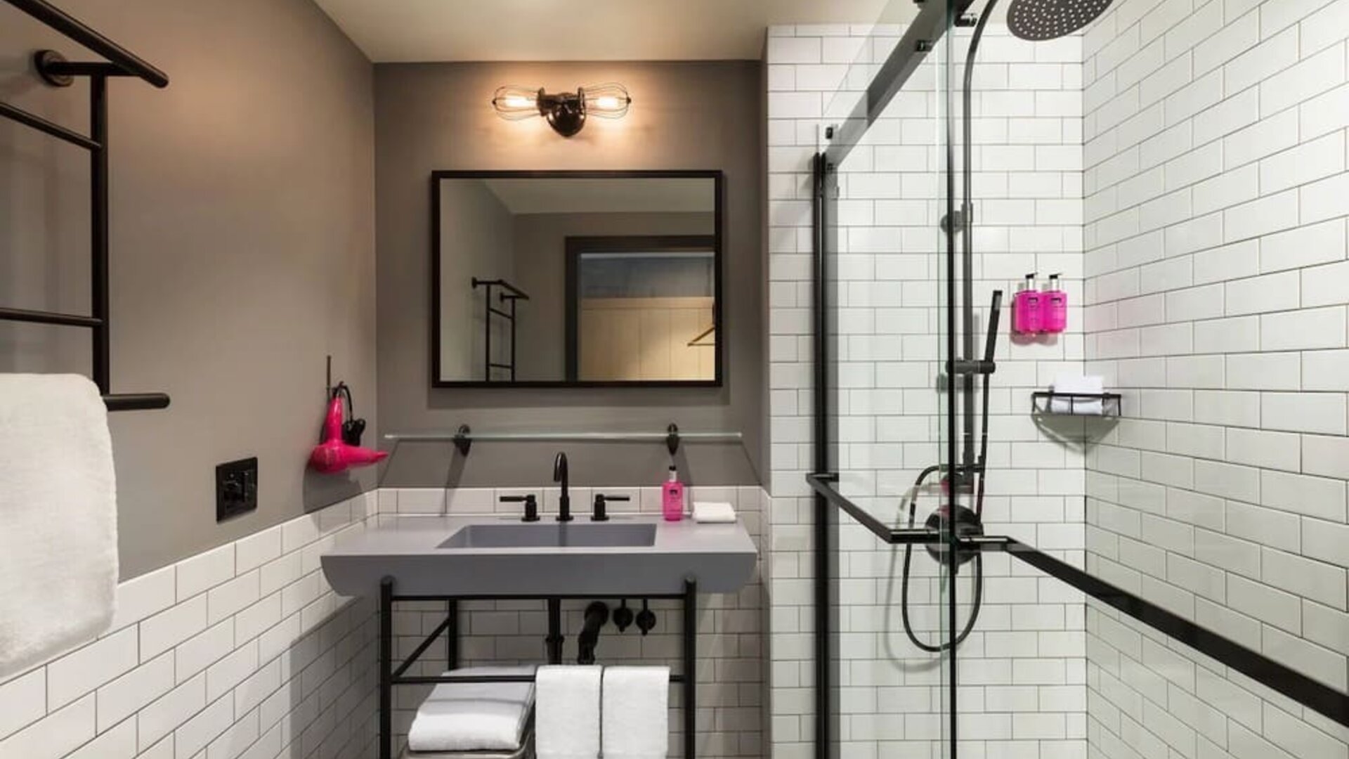 Compact bathroom with rainfall shower, subway tile walls, and floating vanity at Moxy Boston Downtown.