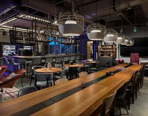 Stylish dining and lounge area with communal tables and pendant lighting at Moxy Boston Downtown.