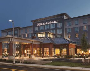 Evening exterior view of Hilton Garden Inn Boston Logan Airport with illuminated entrance and porte cochère.