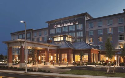 Evening exterior view of Hilton Garden Inn Boston Logan Airport with illuminated entrance and porte cochère.