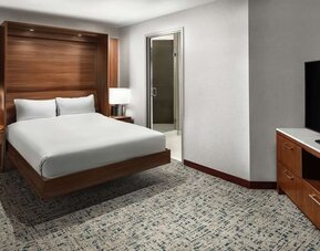 Guest room with platform bed, wood headboard, carpeted floor, and large TV at Hilton Boston Logan Airport.