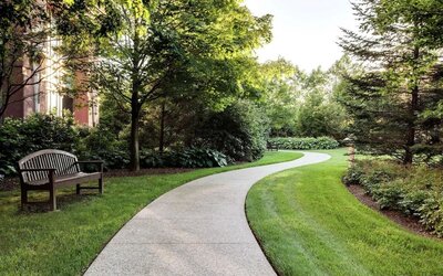 Curved garden walkway with benches, trees, and landscaped greenery at Hilton Boston Logan Airport.