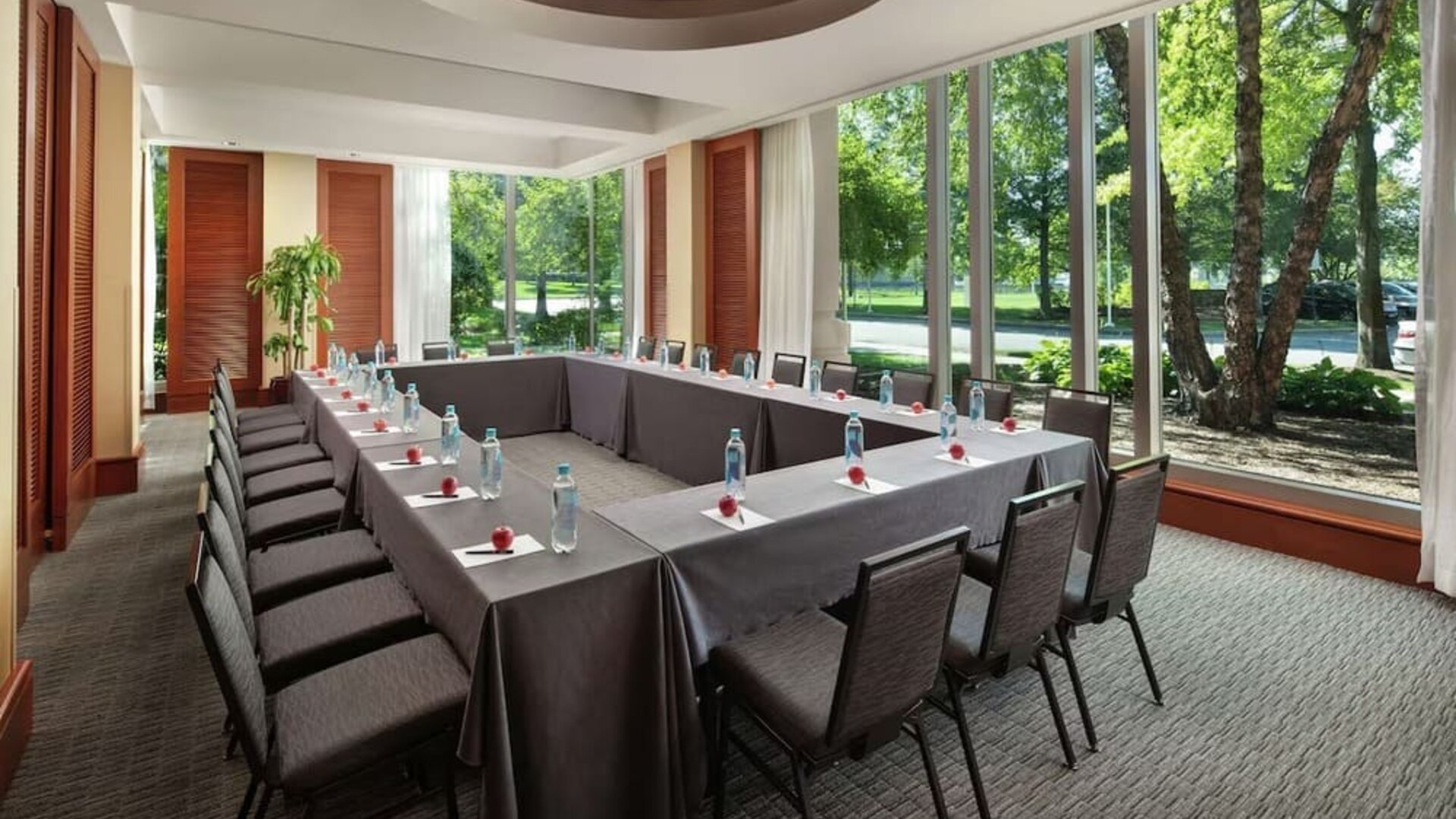 Meeting room with U-shaped conference setup, large windows, and garden views at Hilton Boston Logan Airport.