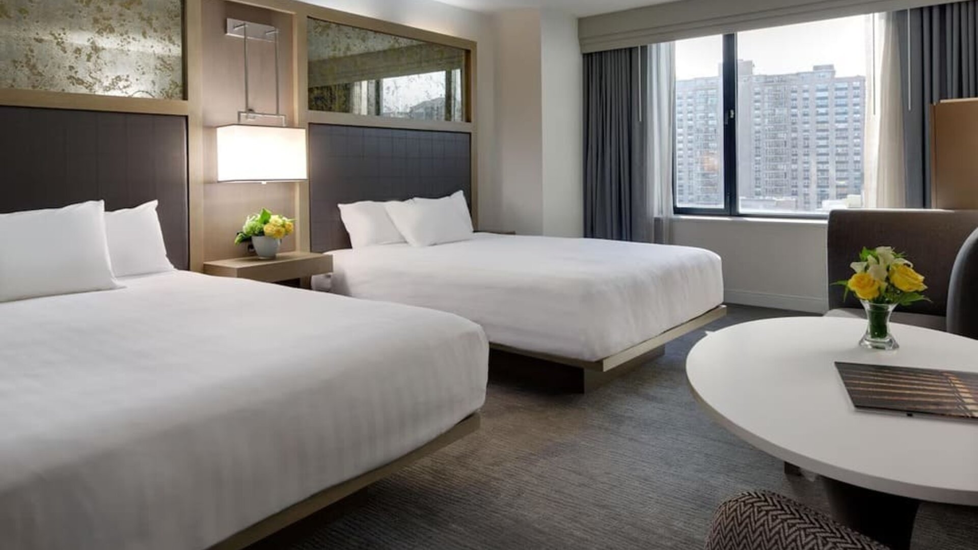 Bright double queen guest room with city views, modern décor, and round table seating at Hyatt Regency Boston.