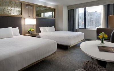 Bright double queen guest room with city views, modern décor, and round table seating at Hyatt Regency Boston.