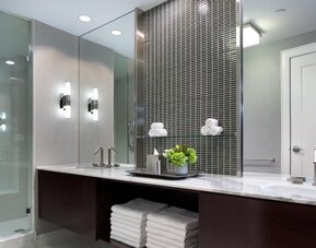Modern hotel bathroom with marble vanity, glass walk-in shower, and contemporary lighting at Hyatt Regency Boston.