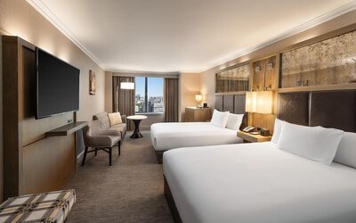 Spacious double queen guest room with city views, seating area, and large flat-screen TV at Hyatt Regency Boston.