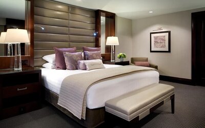 Luxury guest room with king bed, padded headboard, upholstered bench, and elegant neutral décor at Hyatt Regency Boston.