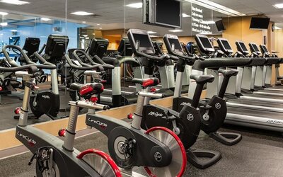 Fully equipped fitness center with treadmills, stationary bikes, and mirrored walls at Hyatt Regency Boston.