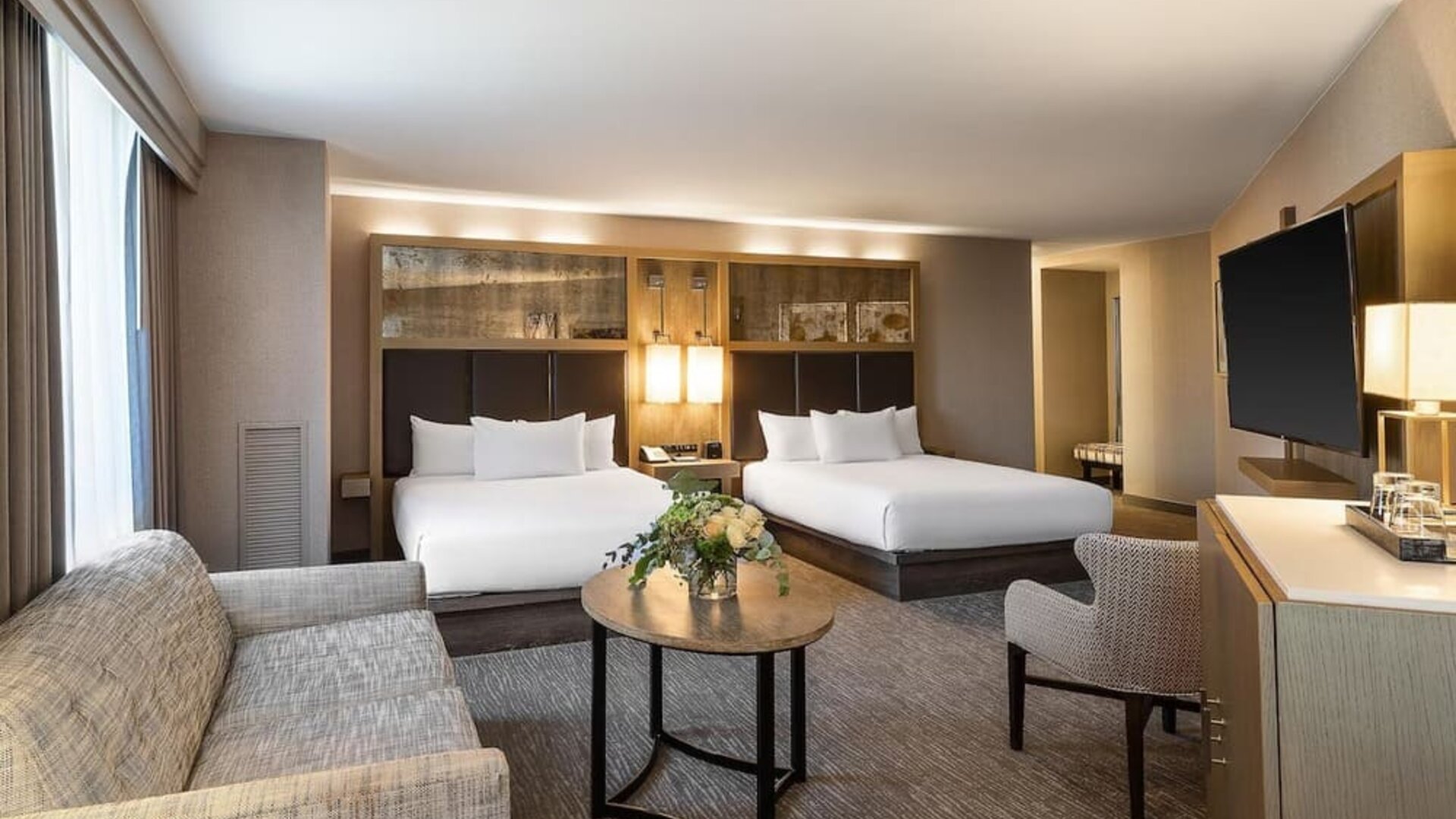 Spacious suite-style guest room with two queen beds, seating area, and modern furnishings at Hyatt Regency Boston.