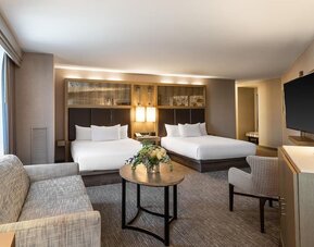 Spacious suite-style guest room with two queen beds, seating area, and modern furnishings at Hyatt Regency Boston.