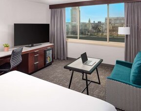 Modern guest room with city and river views, workspace, lounge seating, and large flat-screen TV at Hyatt Regency Boston/Cambridge.