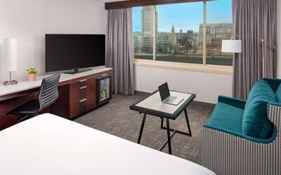 Modern guest room with city and river views, workspace, lounge seating, and large flat-screen TV at Hyatt Regency Boston/Cambridge.