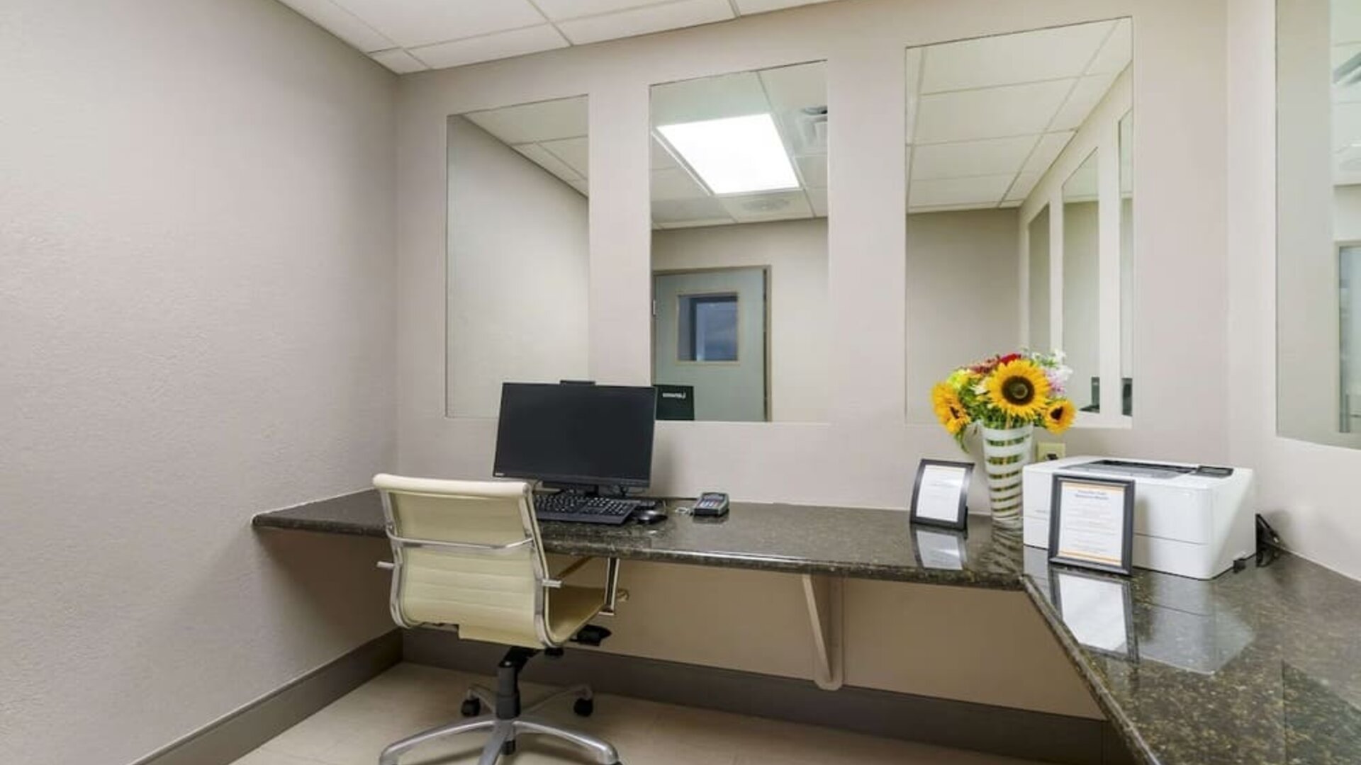 Compact business center with desktop workstation, printer access, and granite work surfaces at Comfort Inn & Suites Port Charlotte-Punta Gorda.