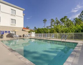 Outdoor swimming pool with surrounding sun loungers and peaceful greenery at Comfort Inn & Suites Port Charlotte-Punta Gorda.
