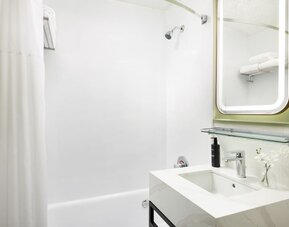 Bright guest bathroom with clean white finishes, modern vanity, and walk-in shower at Row NYC.