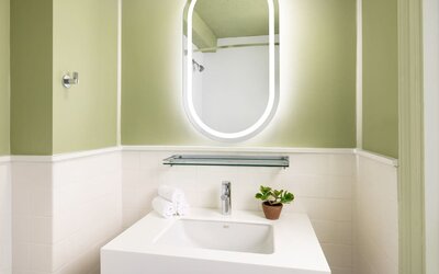 Compact modern bathroom with illuminated mirror, sleek vanity, and contemporary finishes at Row NYC.