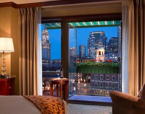 Guest room with scenic balcony and panoramic Boston skyline views at The Bostonian Boston, A Millennium Hotel.