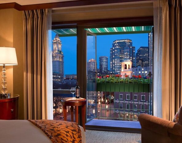 Guest room with scenic balcony and panoramic Boston skyline views at The Bostonian Boston, A Millennium Hotel.