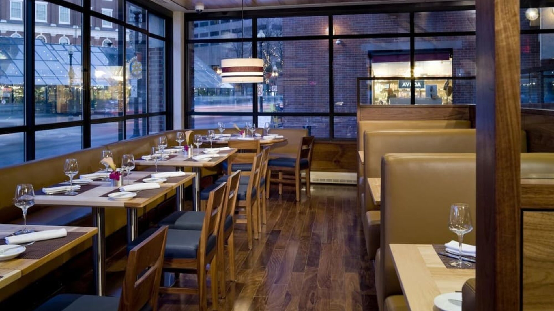 Stylish dining area with floor-to-ceiling windows, cozy booth seating, and contemporary restaurant design at The Bostonian Boston, A Millennium Hotel.