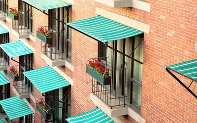 Exterior detail of The Bostonian Boston, A Millennium Hotel featuring charming balconies with striped awnings and flower boxes overlooking the city.