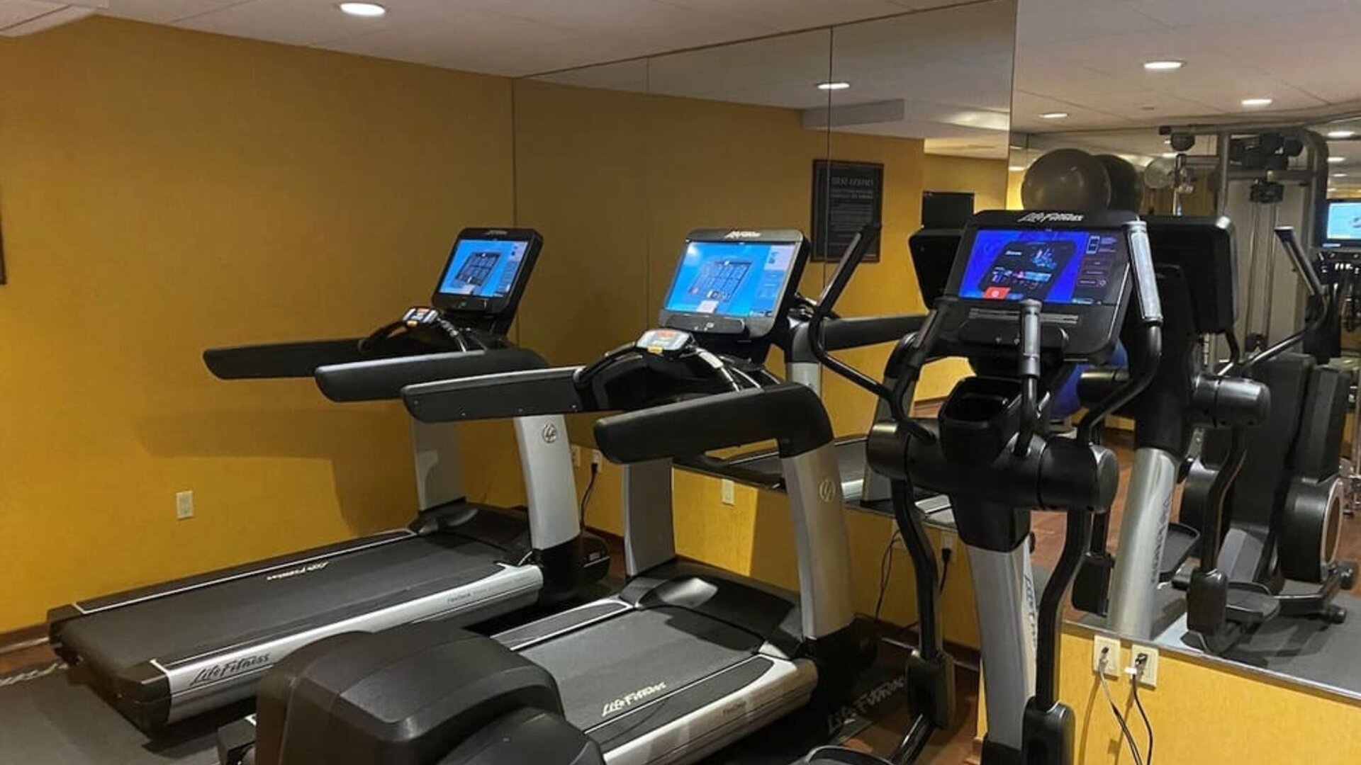Modern hotel gym with treadmills, elliptical machines, and mirrored workout space at The Bostonian Boston, A Millennium Hotel.
