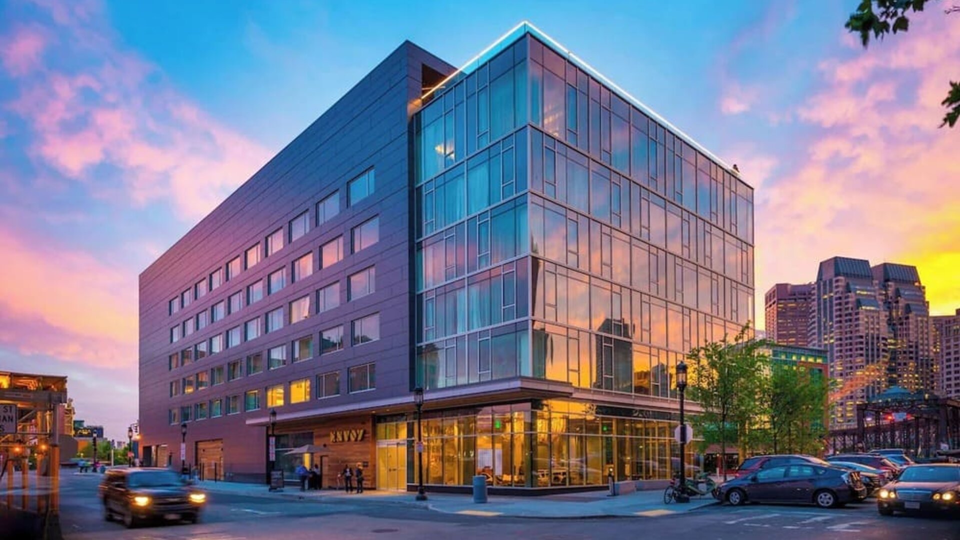 Modern glass-front hotel exterior at sunset showcasing contemporary architecture in Boston’s Seaport District at The Envoy Hotel, Autograph Collection.