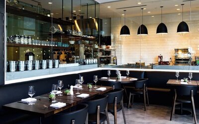 Chic restaurant dining area with open kitchen concept, elegant lighting, and contemporary seating at The Envoy Hotel, Autograph Collection.