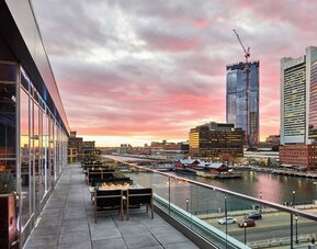 Panoramic rooftop terrace view featuring Boston skyline and waterfront scenery at sunset from The Envoy Hotel, Autograph Collection.