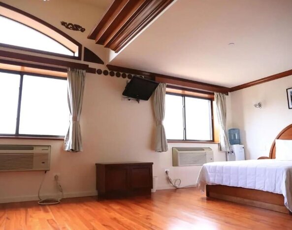 Spacious guest room with hardwood flooring, large windows, and natural light at Phoenix Hotel Brooklyn Sunset Park.