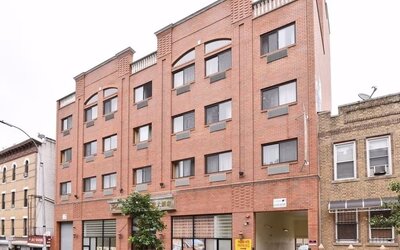 Wide exterior shot of Phoenix Hotel Brooklyn Sunset Park showcasing the multi-story brick building with on-site parking access.