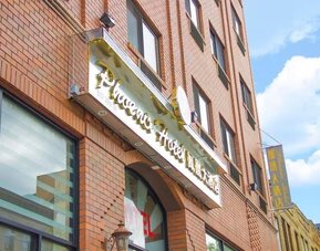 Close-up of the hotel entrance signage at Phoenix Hotel Brooklyn Sunset Park with bilingual branding and urban architectural details.