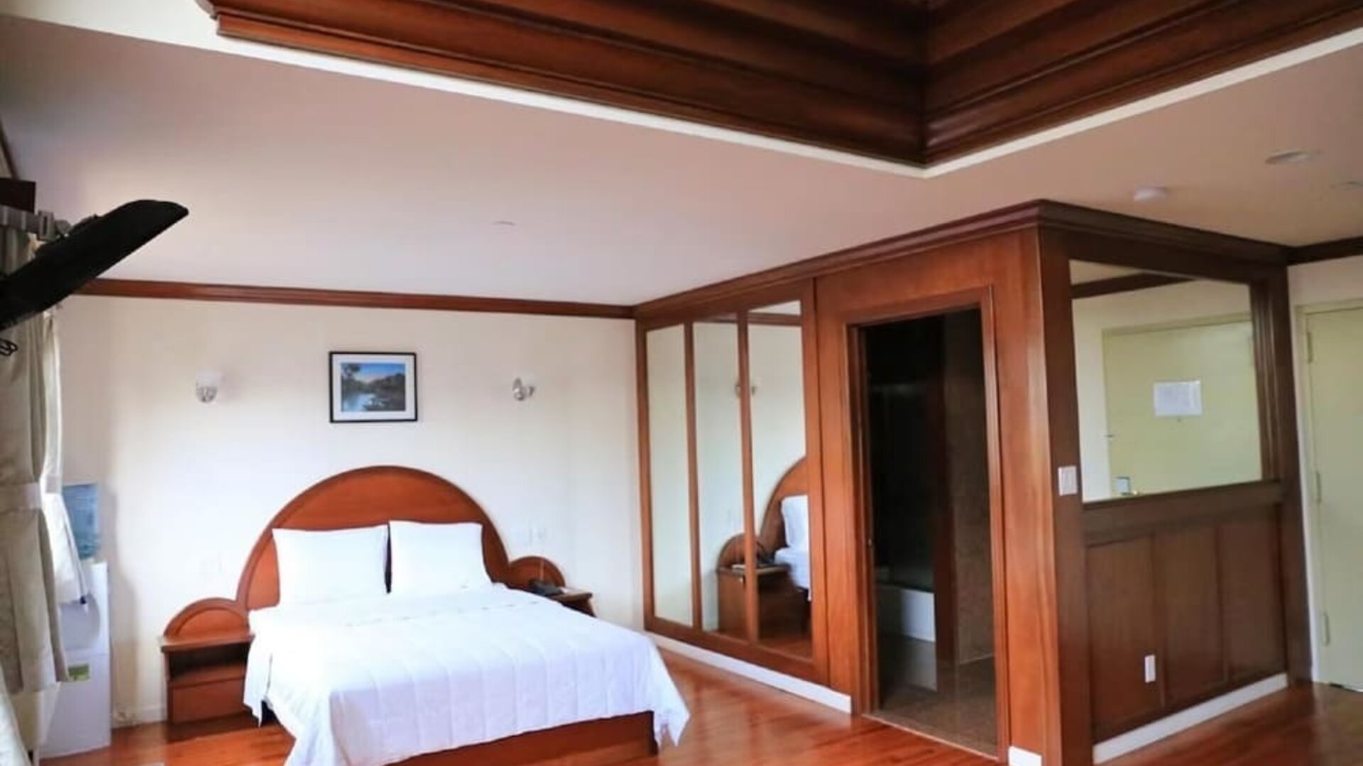 Large king guest suite with polished wood finishes, mirrored wardrobes, and elegant ceiling detailing at Phoenix Hotel Brooklyn Sunset Park.
