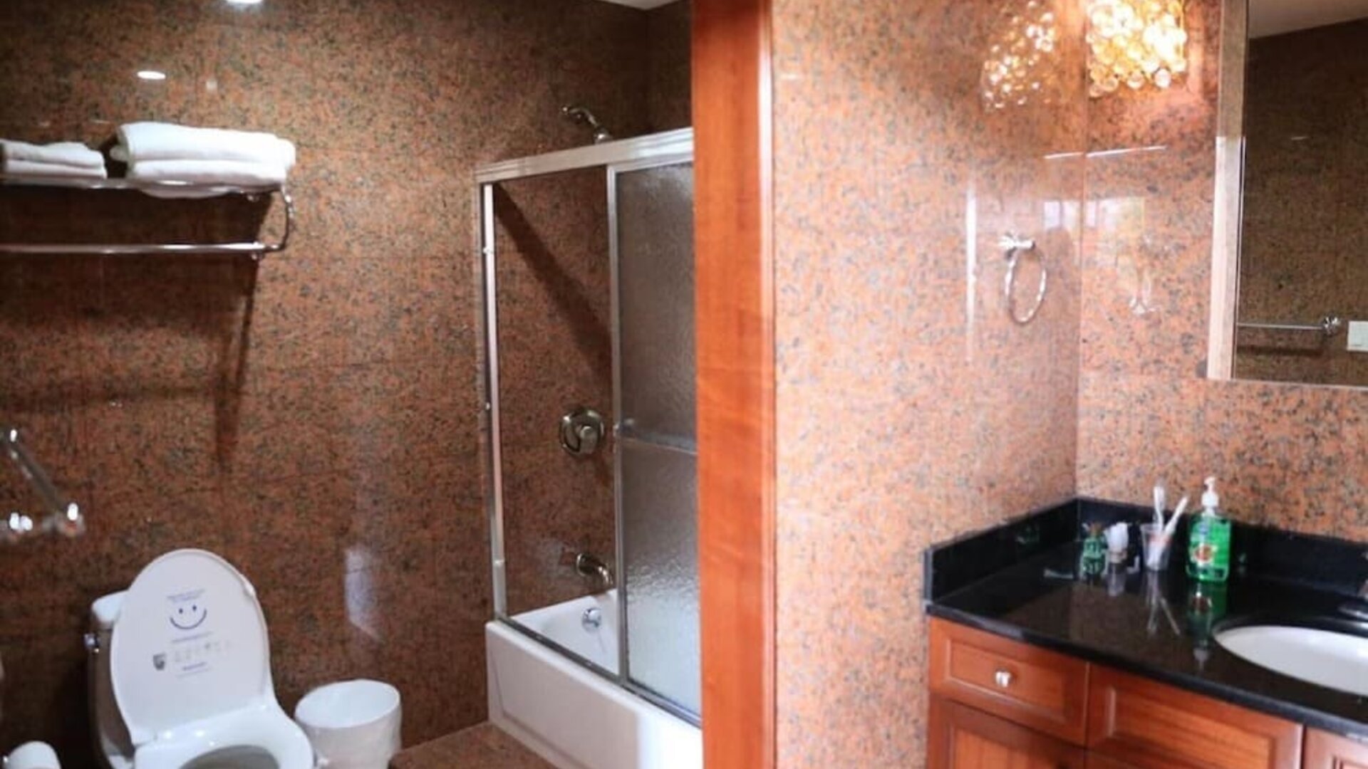 Modern bathroom with granite-style walls, glass shower enclosure, and vanity sink at Phoenix Hotel Brooklyn Sunset Park.