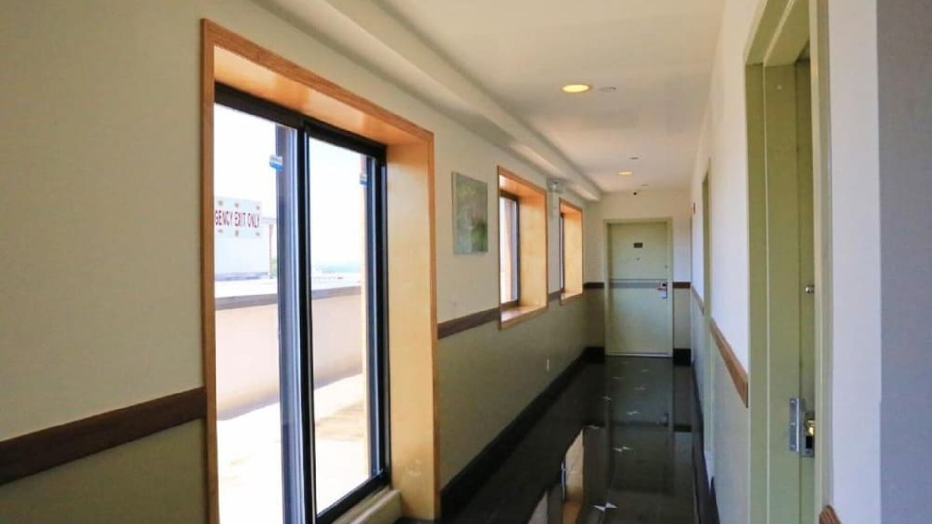 Clean and modern hotel corridor with large windows allowing natural daylight into the passageway at Phoenix Hotel Brooklyn Sunset Park.