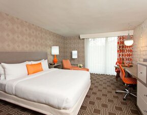 Spacious king guest room with private balcony access, work desk, and vibrant accent furnishings at The Garland.
