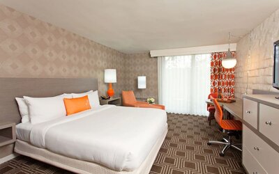 Spacious king guest room with private balcony access, work desk, and vibrant accent furnishings at The Garland.