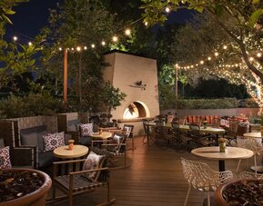 Charming outdoor dining patio with string lighting, fireplace feature, and garden-inspired seating at The Garland.
