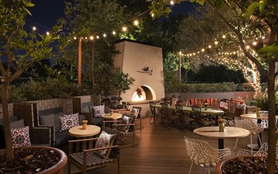 Charming outdoor dining patio with string lighting, fireplace feature, and garden-inspired seating at The Garland.