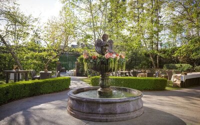 Beautiful landscaped garden courtyard with a decorative fountain surrounded by lush greenery and outdoor seating at The Garland.