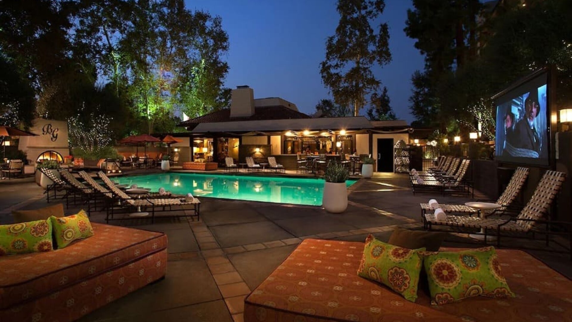 Resort-style outdoor swimming pool area with lounge chairs, evening lighting, and open-air relaxation spaces at The Garland.