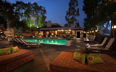 Resort-style outdoor swimming pool area with lounge chairs, evening lighting, and open-air relaxation spaces at The Garland.