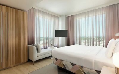 Bright guest room with a king-size bed, floor-to-ceiling windows, comfortable seating area, and panoramic views of the surrounding Anaheim area.