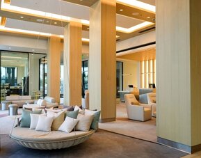 Grand lobby at The Viv Hotel, Anaheim, A Tribute Portfolio Hotel featuring high ceilings, elegant wood accents, lounge seating, and contemporary architectural design.