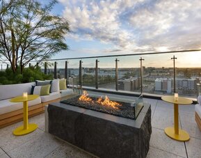 Rooftop terrace with fire pit seating, city views, and comfortable outdoor lounges, ideal for social gatherings and sunset relaxation.