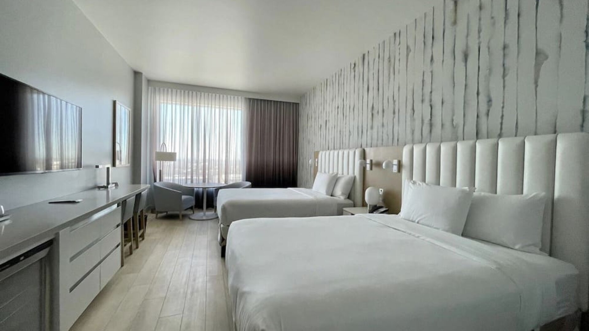 Alternative view of a double-queen guest room highlighting the modern décor, premium bedding, and spacious layout.