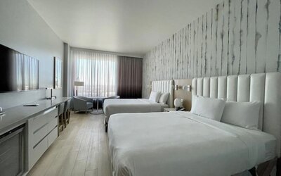 Alternative view of a double-queen guest room highlighting the modern décor, premium bedding, and spacious layout.