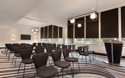 Meeting and event room equipped with modern seating arrangements and presentation facilities suitable for business meetings and small conferences.