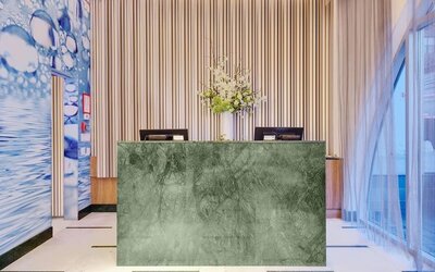 Modern reception area featuring a marble-front front desk, elegant floral arrangements, high ceilings, and a sophisticated lobby design.