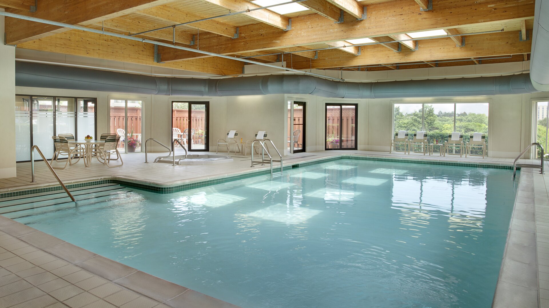 Relaxing indoor pool with lounge chairs at Courtyard By Marriott Toronto Airport.